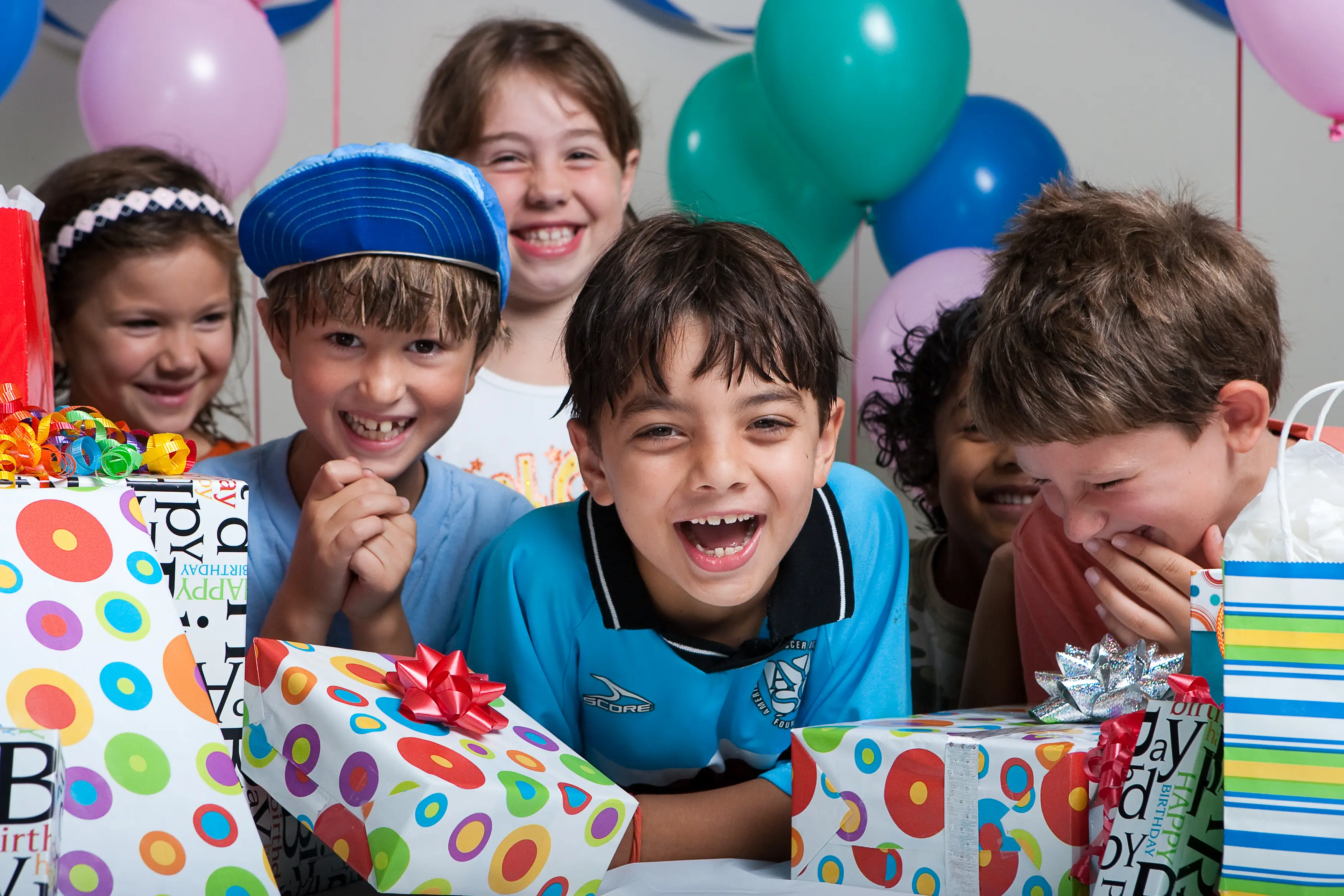 children happy surrounded by birthday presents and balloons